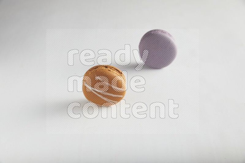 45º Shot of of two assorted Brown Irish Cream, and Purple Blueberry macarons on white background