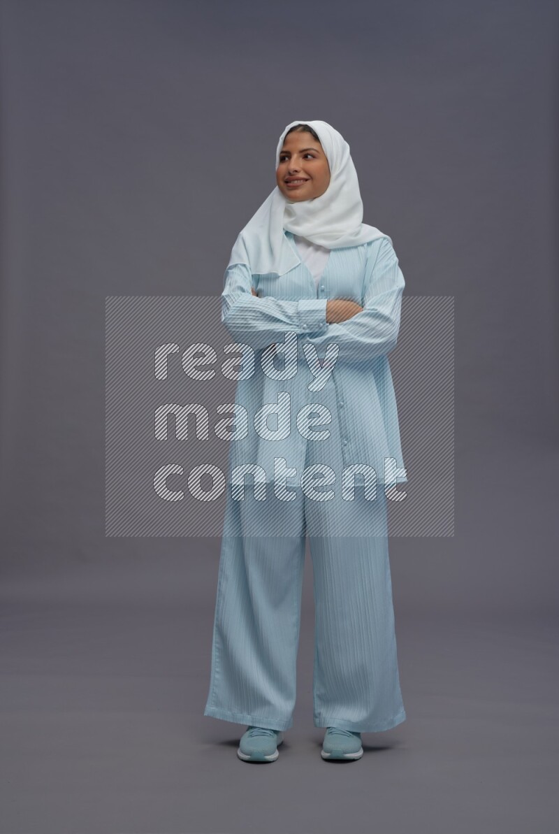 Saudi woman wearing hijab clothes standing with crossed arms on gray background