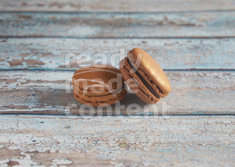 45º Shot of of two assorted Brown Irish Cream, and Brown Coffee macarons on light blue background