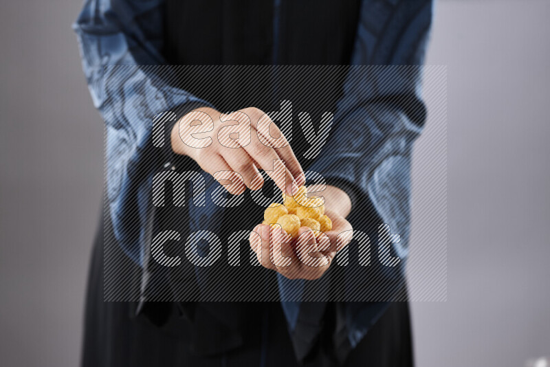 Woman in abaya holding different kinds of snacks in different positions