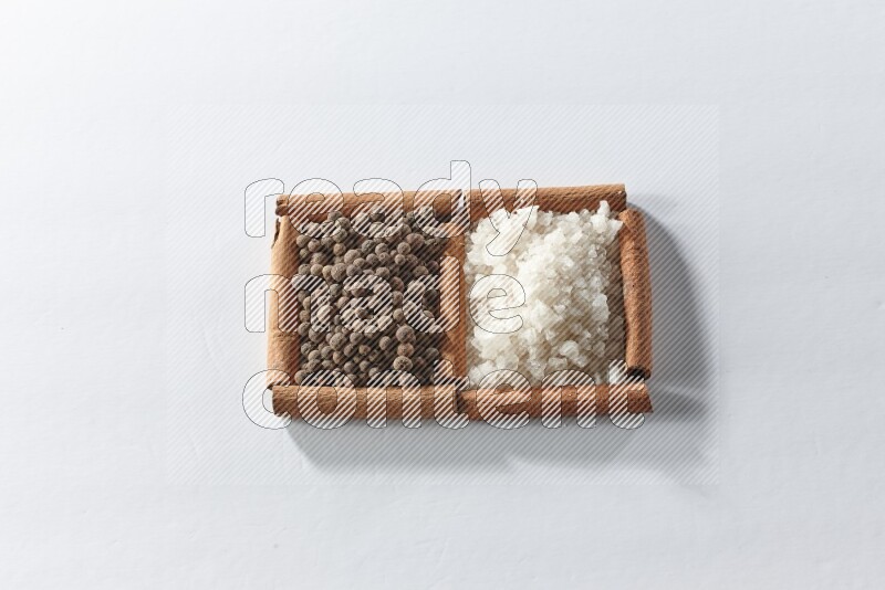 2 squares of cinnamon sticks full of white salt and allspice on white flooring