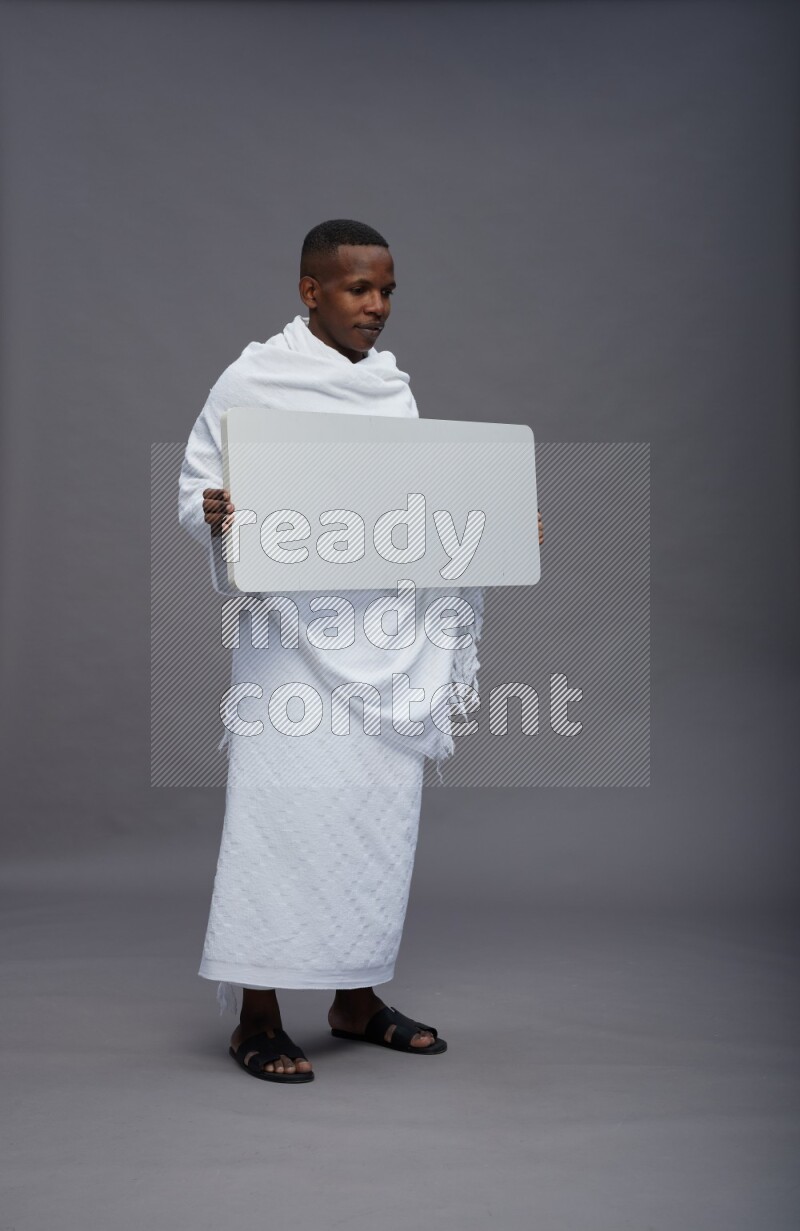 A man wearing Ehram Standing holding board sign on gray background