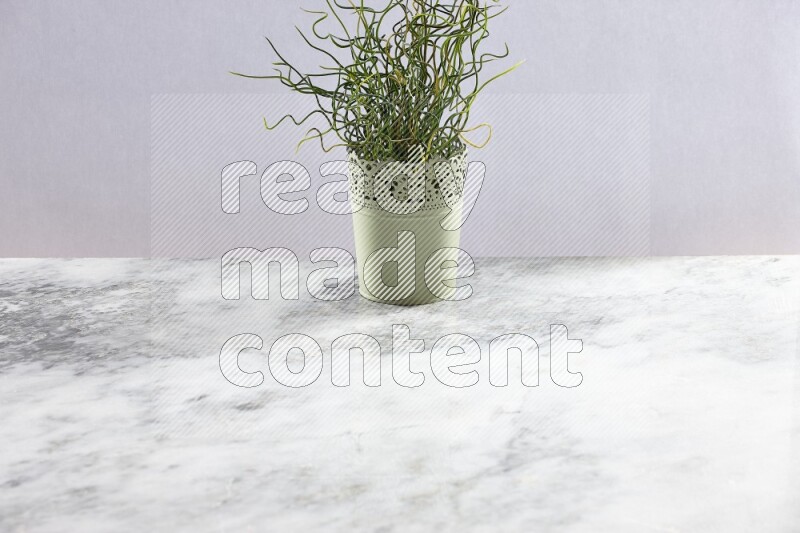 Artificial plant in green decorative pot on grey marble background