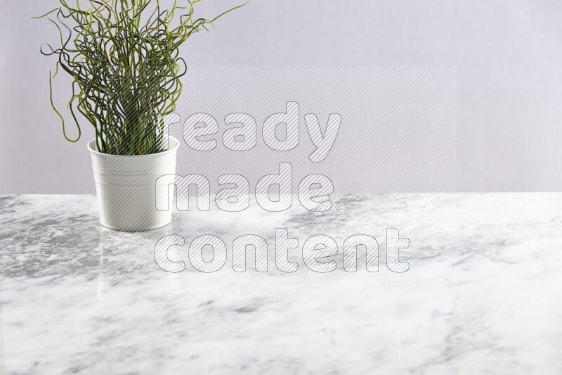 Green artificial plant in white pot on light grey marble background