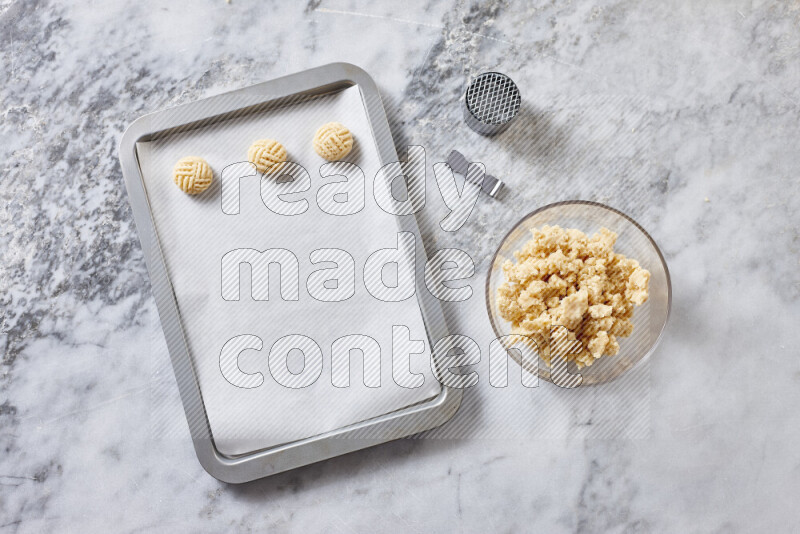 كحك خطوة بخطوة بمكوناته سمن، سكر، دقيق، سمسم، خميرة، ماء ونكهة الكحك على خلفية رخام رمادي