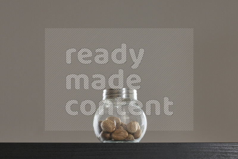 جوزة الطيب في وعاء زجاجي على خلفية سوداء