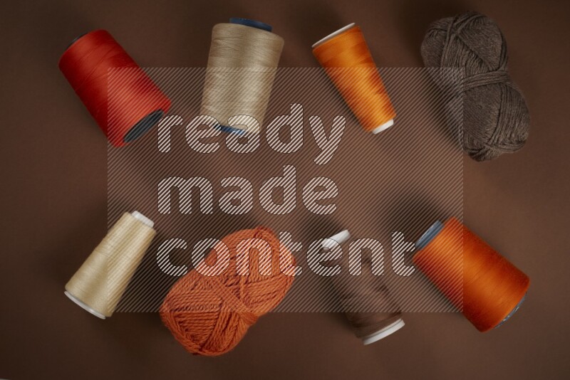 An orange collection of sewing and tailoring tools arranged on a brown background