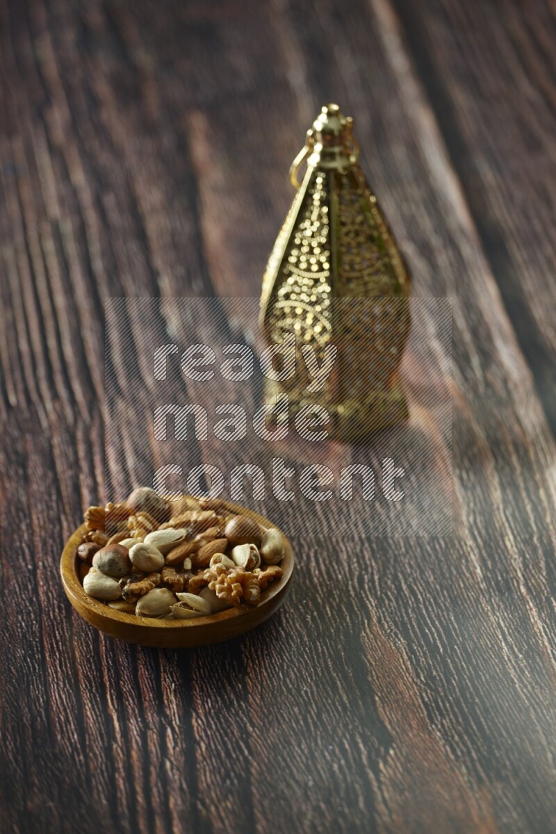 A golden lantern with different drinks, dates, nuts, prayer beads and quran on brown wooden background