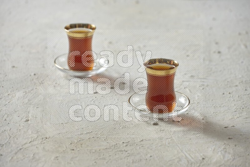 A tea glass cup with dates and coffee on textured white background