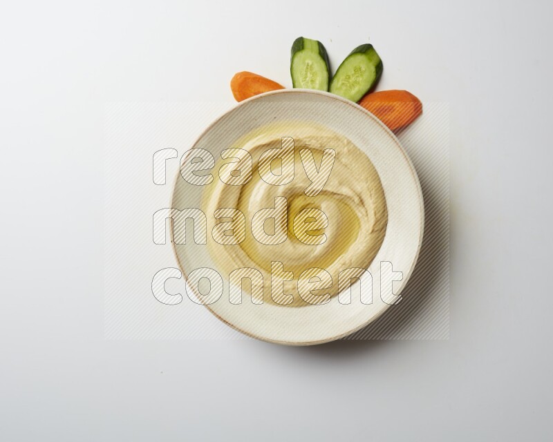 Hummus in a pottry plate garnished with olive oil on a white background