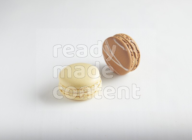 45º Shot of of two assorted Brown Irish Cream, and Yellow Vanilla macarons on white background