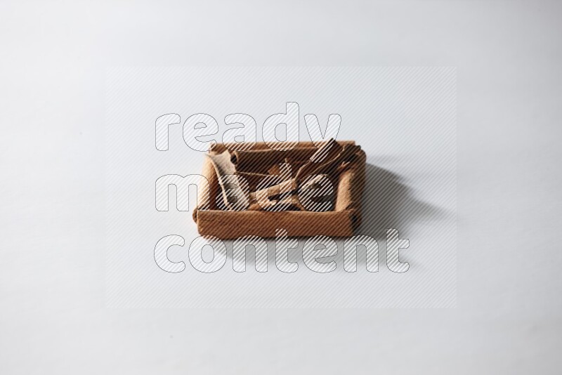 أربعة من أعواد القرفة مكونة شكل مربع بداخلها أعواد قرفة صغيرة علي خلفية بيضاء