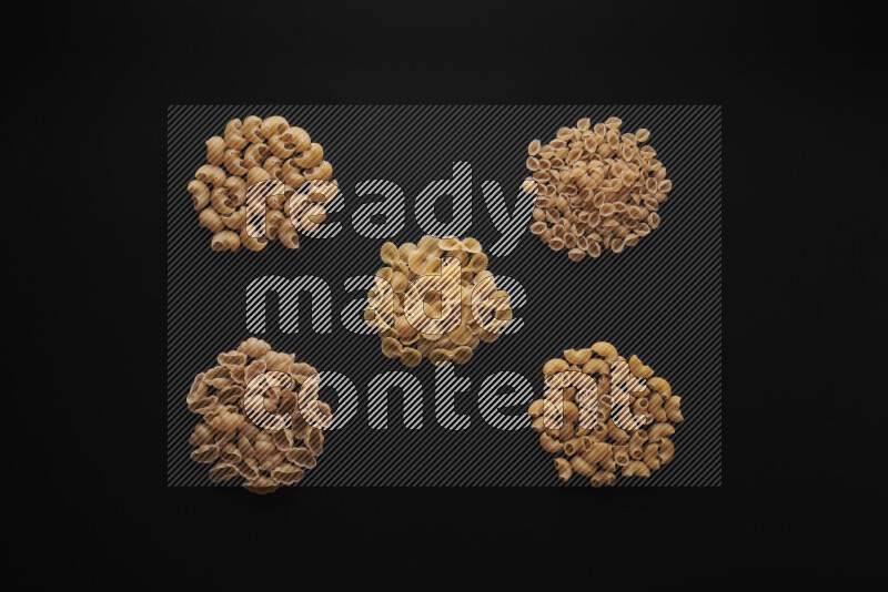 Different pasta types in bunches on black background