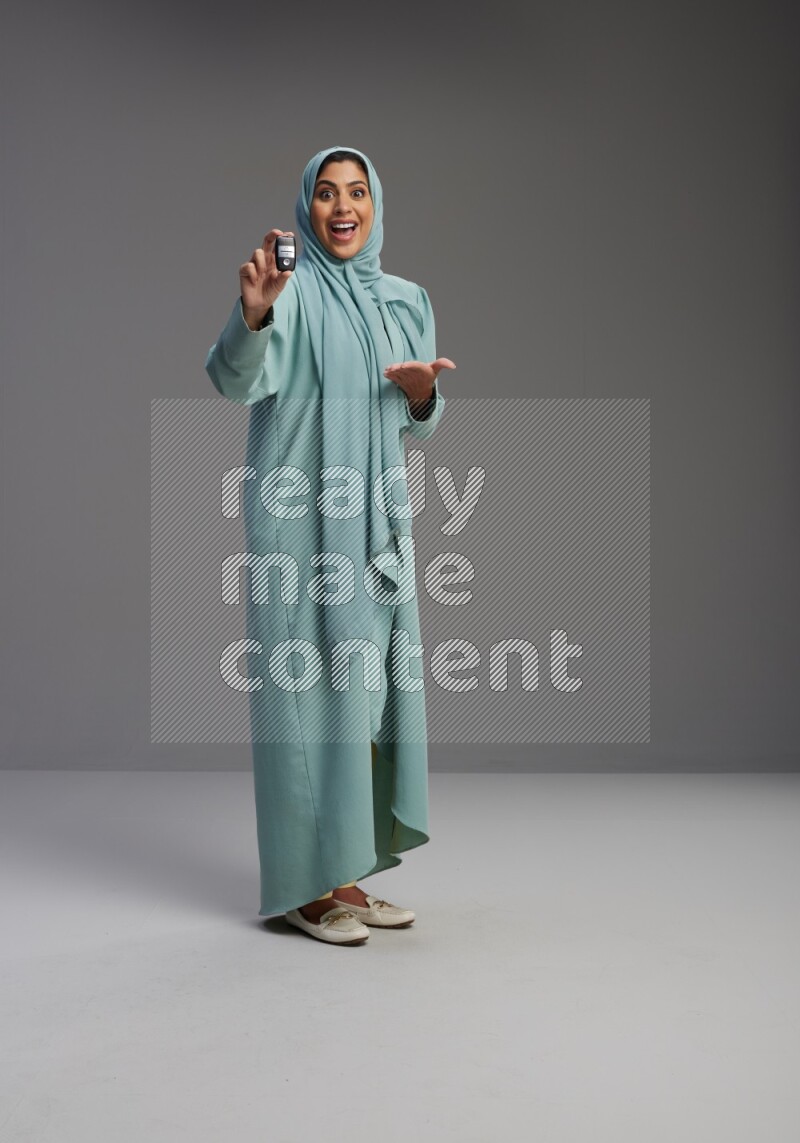 Saudi Woman wearing Abaya standing holding car key on Gray background