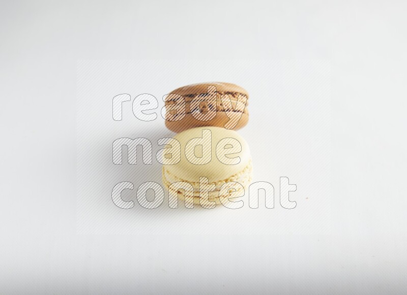 45º Shot of of two assorted Brown Irish Cream, and Yellow Vanilla macarons on white background