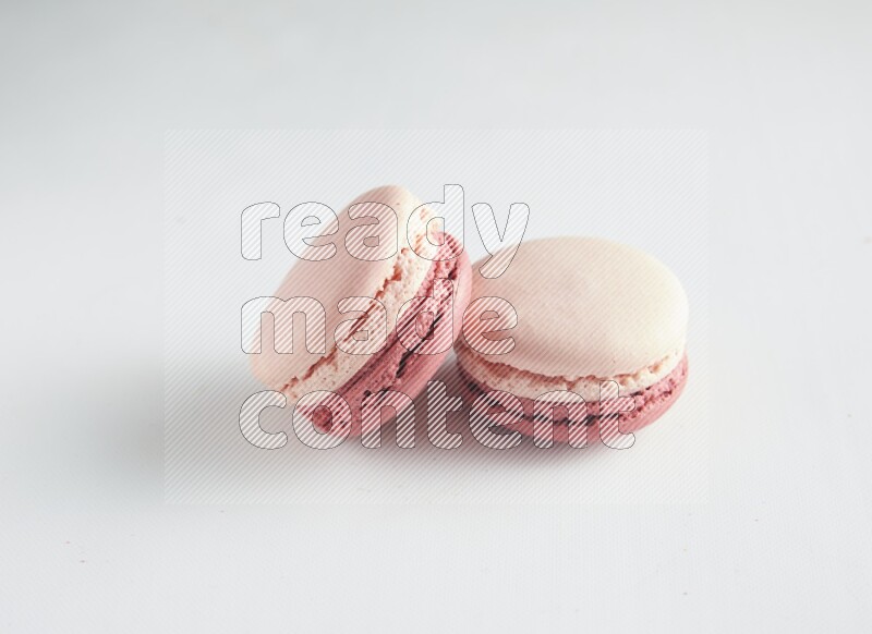 45º Shot of two Pink Litchi Raspberry macarons on white background