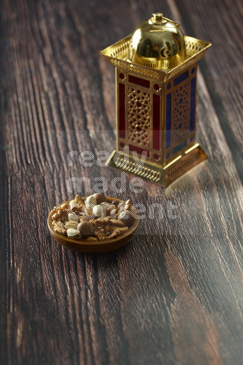 A golden lantern with different drinks, dates, nuts, prayer beads and quran on brown wooden background