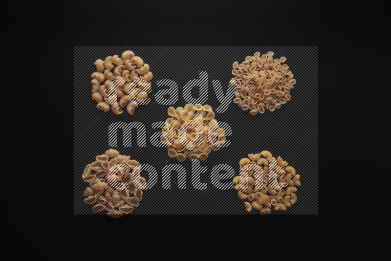 Different pasta types in bunches on black background