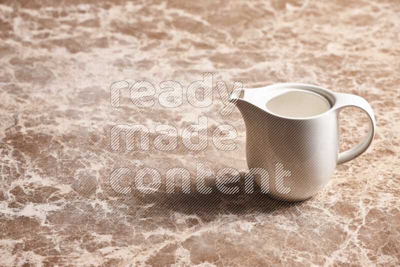 A ceramic milk jug on beige marble background