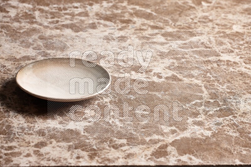 A beige pottery plate on beige marble background