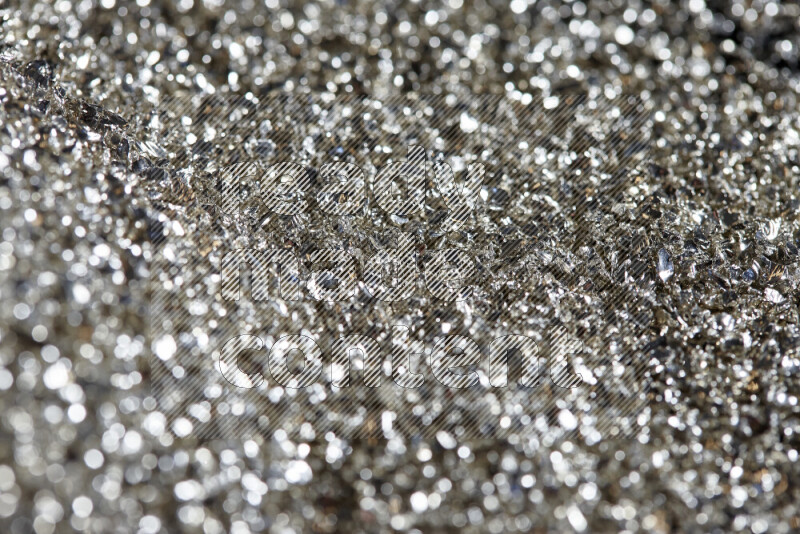 Silver shimmering fragments of glass scattered on a black background