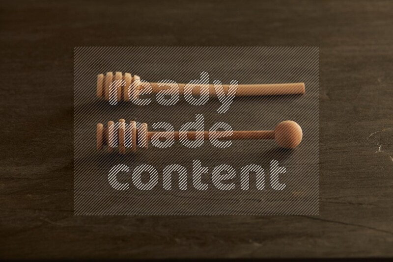 Wooden honey dipper on black slate background
