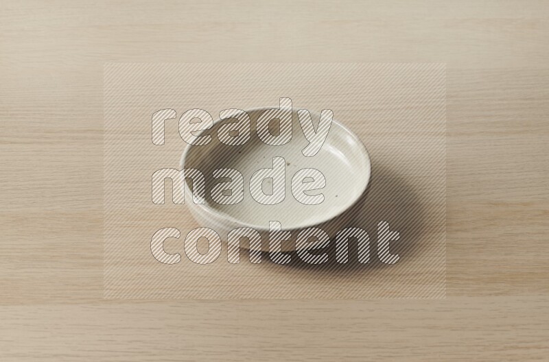 A beige pottery bowl on light wooden background