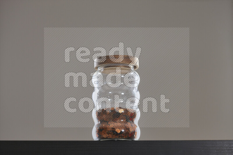 Sequins in a glass jar on black background