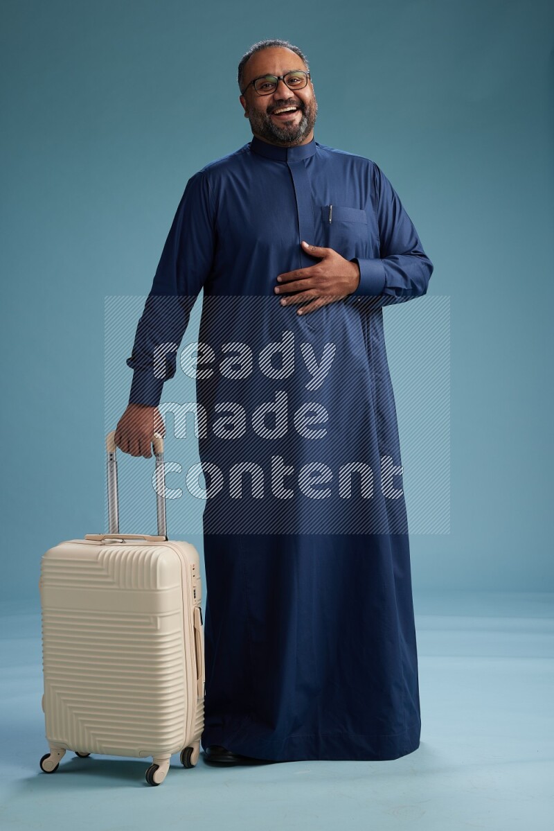 Saudi Man without shimag Standing pulling travel bag on blue background