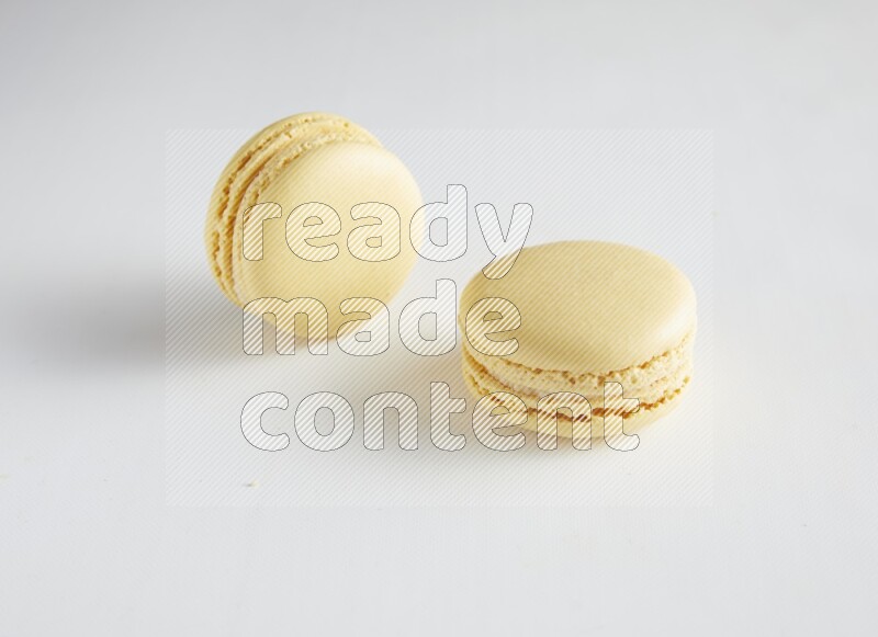 45º Shot of two Yellow Vanilla macarons on white background