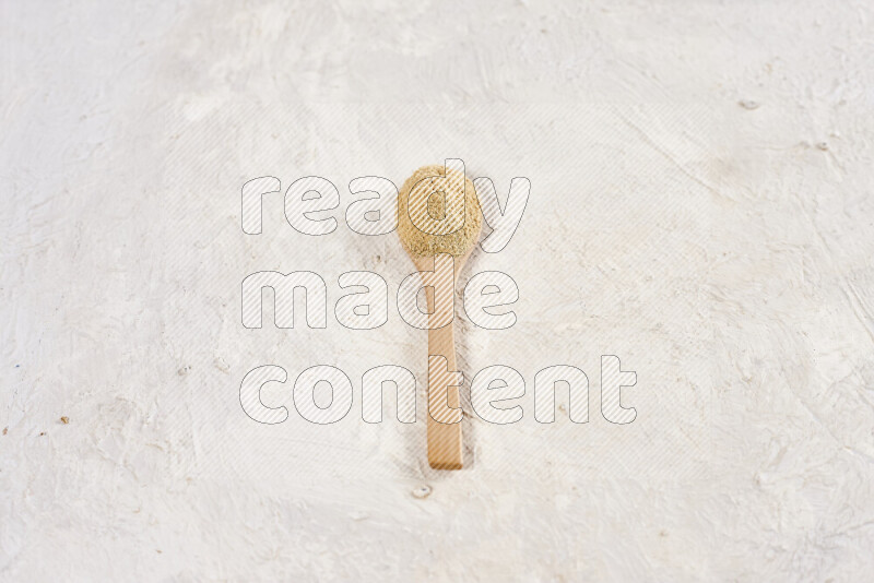 A wooden spoon full of ground ginger powder on white background