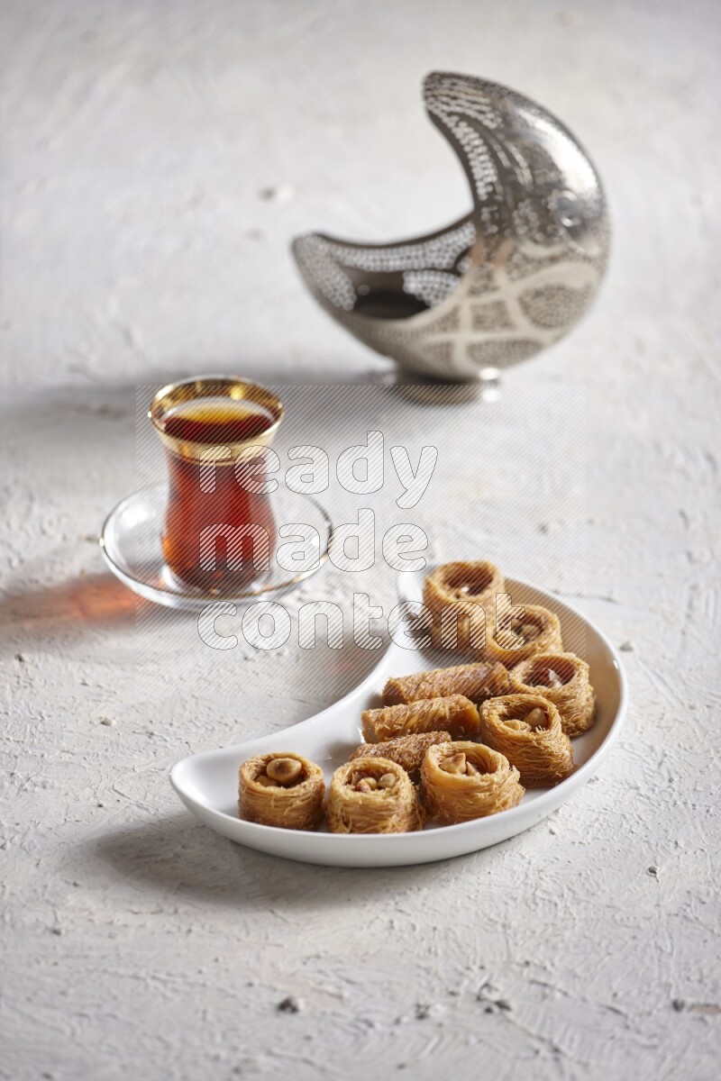 Konafa in a pottery plate with lantern and tea in a light setup