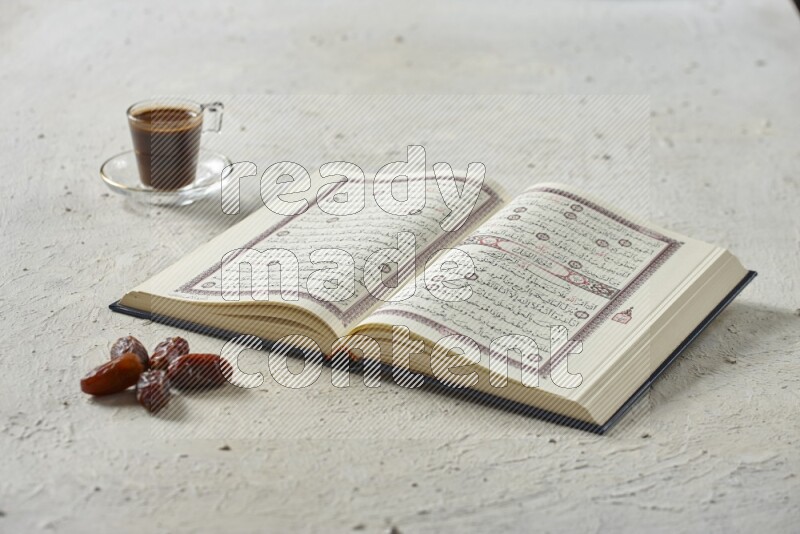 Quran with dates, prayer beads and different drinks all placed on textured white background