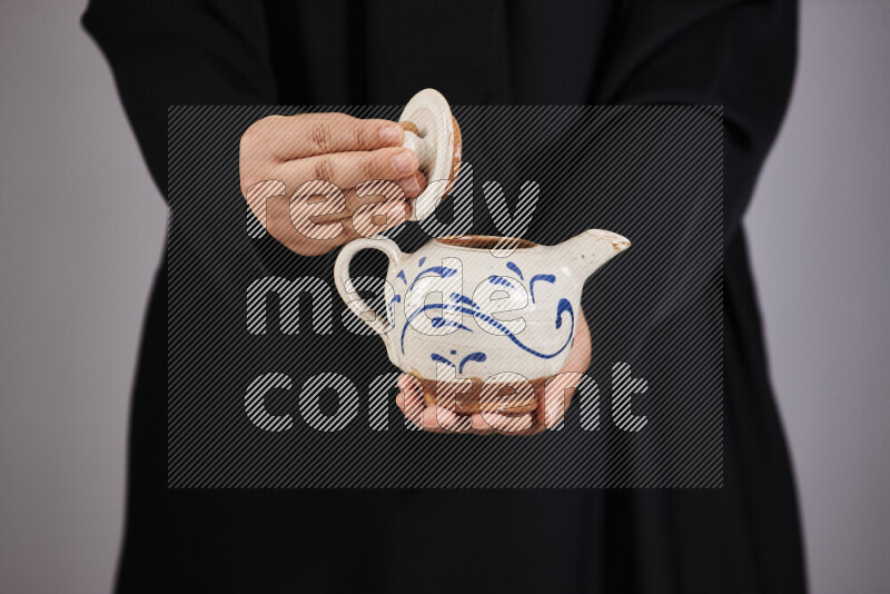 A woman in black abaya holding different pottery essentials in different positions