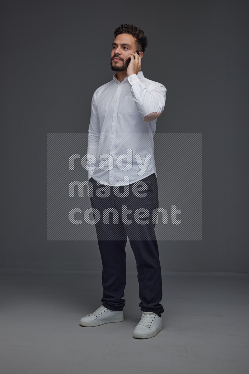 A man wearing smart casual talking in the phone eye level on a gray background