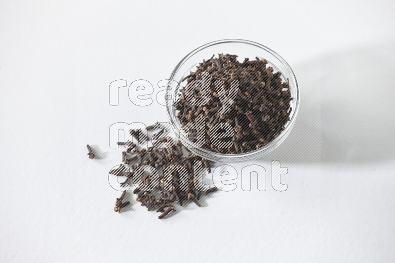 A glass bowl full of cloves on a white flooring