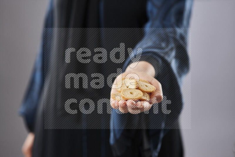 Woman in abaya holding different kinds of snacks in different positions