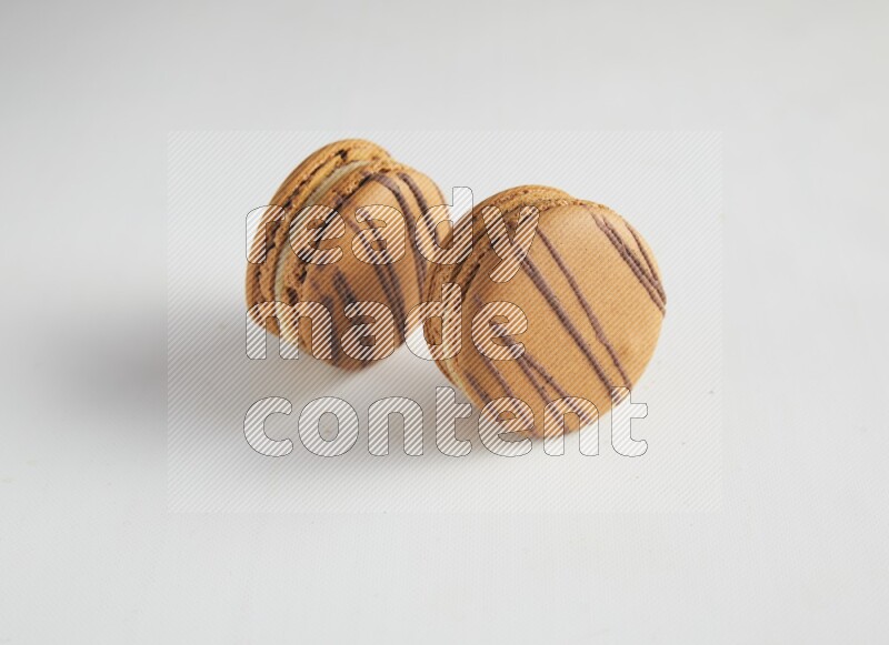 45º Shot of two light brown  Almond Cream macarons on white background