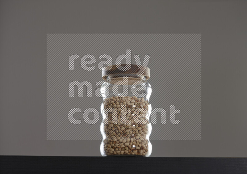 Black-eyed peas in a glass jar on black background