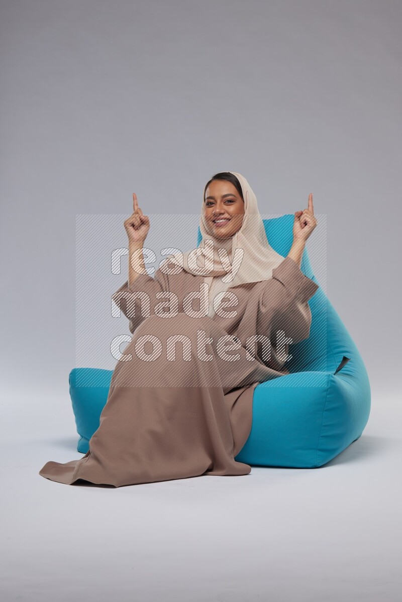 A woman sitting on a blue beanbag and interacting with the camera