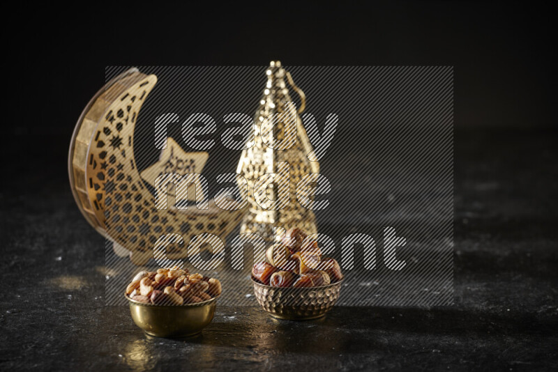 تمر في وعاء معدني مع المكسرات بجانب فوانيس ذهبية علي خلفية سوداء