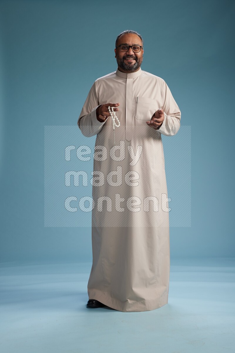 Saudi Man without shimag Standing Interacting with the camera on blue background