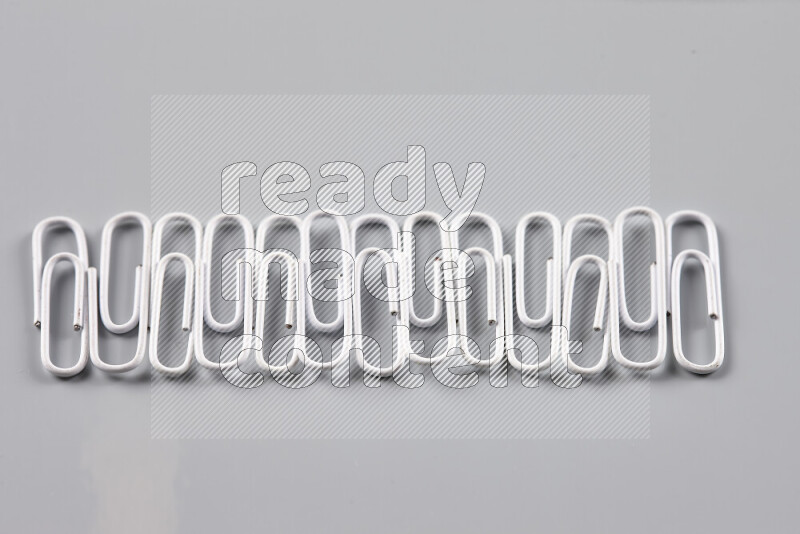White paper clips isolated on a grey background