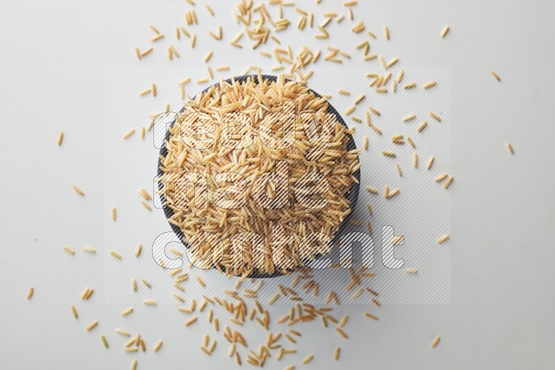 Top-view shot of long grain brown rice in a container on white background