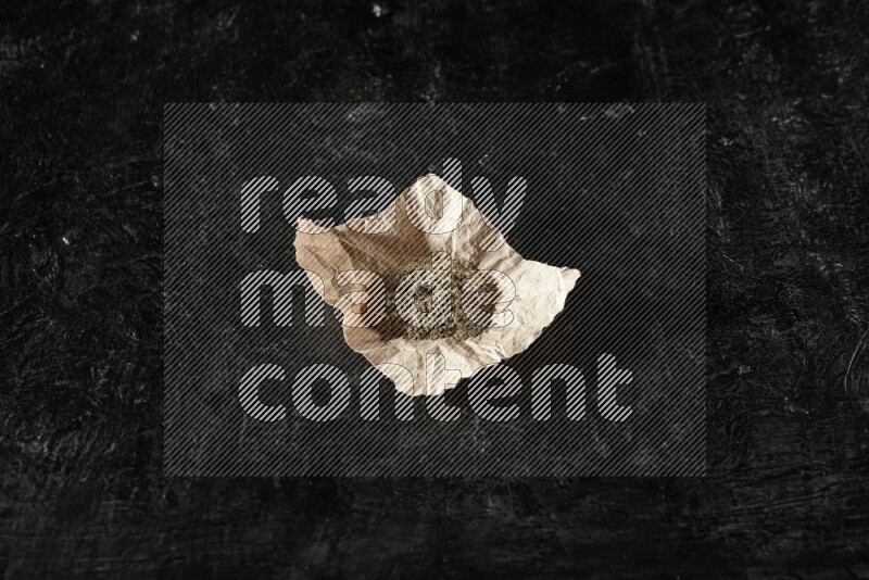 بودرة الهيل في قطعة من الورق على خلفية سوداء