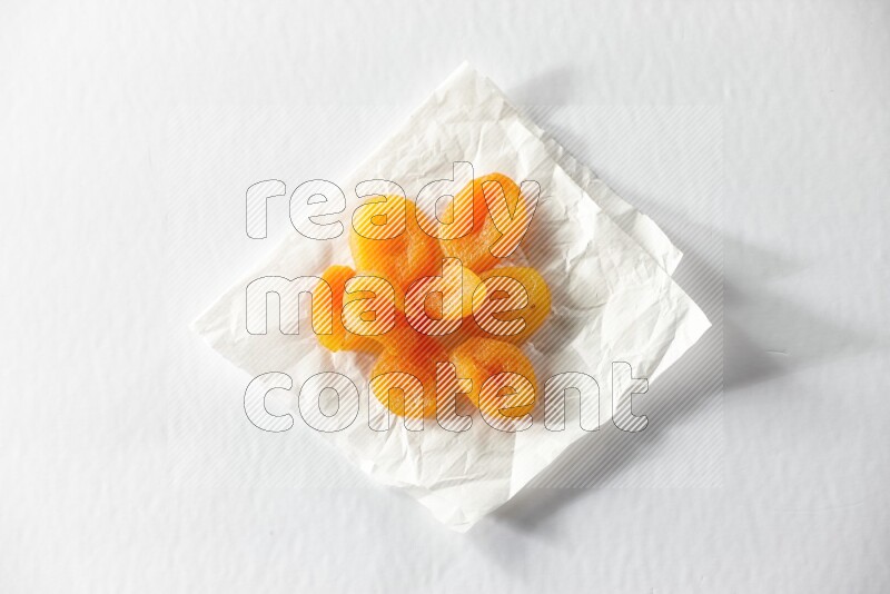 Dried apricots on a crumpled piece of paper on a white background in different angles