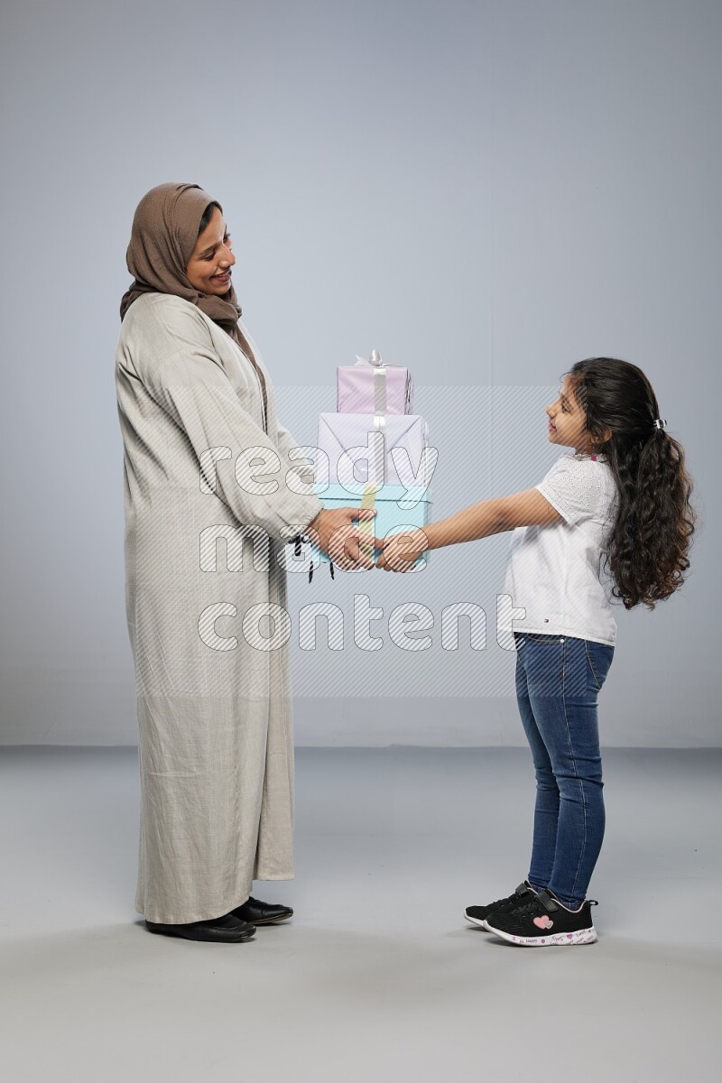 A girl giving a gift to her mother on gray background