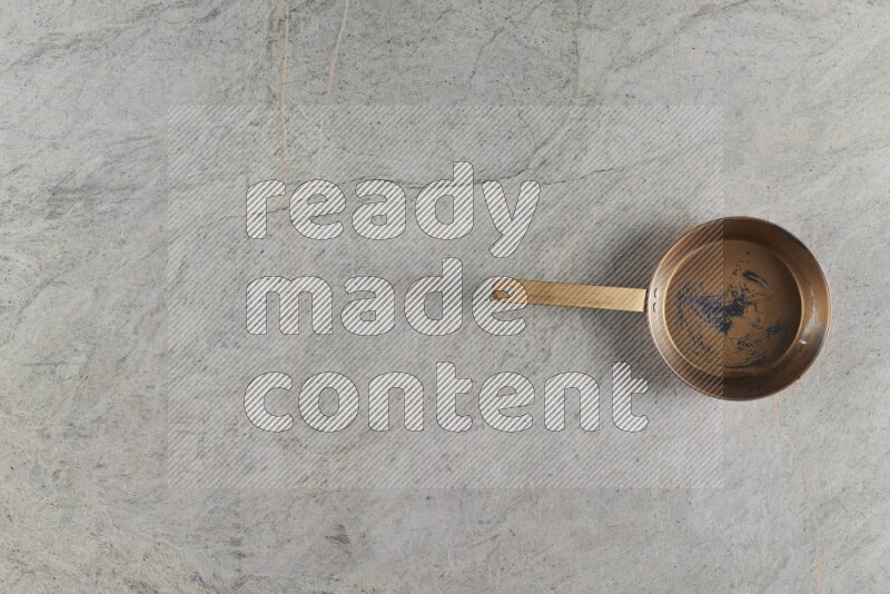 A small copper pan on grey marble background