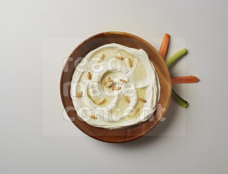 Lebnah garnished with pine nuts in a wooden plate on a white background