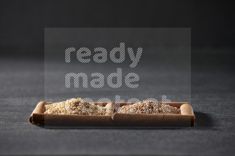 مربعان من أعواد القرفة ممتلئان بحبوب الخردل وبذور السمسم علي خلفية سوداء